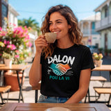 T-shirt noir de femme en situation, porté par une jeune femme souriante sur la terrasse ensoleillée d'un café, avec le design "DALON POU LA VI" et les mains en poignée de main colorée