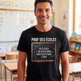 T-shirt noir pour homme porté par un enseignant souriant dans une salle de classe de primaire, avec le design "PROF DES ÉCOLES" et l'équation "25 élèves x 40 questions = 1000 questions/jour" sur une ardoise en craie blanche