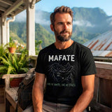 T-shirt noir pour homme en coton porté par un randonneur barbu en pause, assis sur une varangue en bois traditionnelle de La Réunion, avec le visuel de carte et le texte "MAFATE PAS DE ROUTE, PAS DE STRESS" sur le devant