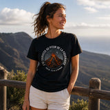 Femme portant un t-shirt noir avec le slogan "J'ai survécu au Piton de la Fournaise" au sommet du Piton des Neiges à La Réunion, paysage volcanique en arrière-plan