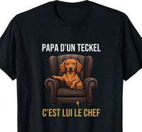Tee-shirt noir pour homme avec un teckel installé dans un fauteuil de direction et le message papa d'un teckel, c'est lui le chef