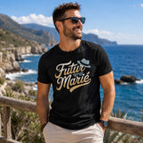 Homme portant un t-shirt noir avec le design « Futur Marié » debout face à l'océan sur un belvédère en bord de mer, souriant dans un décor ensoleillé.