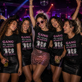 Groupe de femmes portant un t-shirt noir avec le design « Gang des copines déjantées de la mariée » en train de faire la fête dans une boîte de nuit lors d'un enterrement de vie de jeune fille