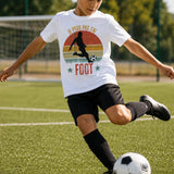 Garçon portant un t-shirt blanc avec l'inscription « Je peux pas j'ai Foot » et une illustration de joueur de football, en train de frapper un ballon sur un terrain de football avec un but et des arbres en arrière-plan.