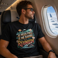 Homme portant un t-shirt noir avec le design « Je peux pas, je me barre à La Réunion » assis à bord d'un avion près du hublot.