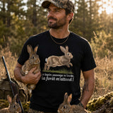 Homme portant un t-shirt noir avec une illustration de lapin sauvage et le texte « Le lapin sauvage m'invite, la forêt m'attend ! », photographié dans une clairière en forêt entouré de plusieurs lapins sauvages au coucher du soleil.