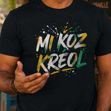 Homme portant un t-shirt noir avec le design « Mi Koz Kréol » en train de discuter avec un autre homme devant un bar créole tropical.