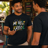Homme portant un t-shirt noir avec le design « Mi Koz Kréol » en pleine conversation sur la terrasse d'un bar créole sous les tropiques.