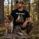 Homme portant un t-shirt noir avec le texte « MON CHIEN CHASSE MIEUX QUE MOI » et une illustration d'un chien de chasse, photographié en forêt avec son chien et un gibier après une journée de chasse.