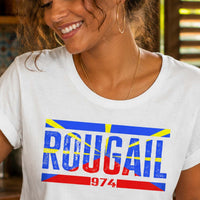 Femme portant un t-shirt blanc avec le design « Rougail 974 » en préparant un rougail saucisse dans une cuisine créole traditionnelle de La Réunion.
