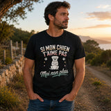 Homme portant un t-shirt noir avec le design « Si mon chien t'aime pas, moi non plus » lors d'une balade en pleine nature avec son chien.