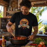 Homme portant un t-shirt noir avec le design « Team Rougail Saucisse » en train de cuisiner un rougail saucisse dans une cuisine créole à La Réunion.